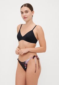 Sort trekantet bikini top med tynde stropper og en low-rise multicolor bikini bund med bindeside lukninger og et gradientmønster.