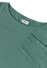 Grön långärmad t-shirt i mjukt tyg, med rund halsringning och subtil textur. Etiketten säger "CECIL."