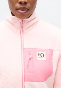 Φούξια ροζ φλις μπουφάν με τσέπη στο στήθος με φερμουάρ σε πιο σκούρο ροζ, με ετικέτα λογότυπου. Μαλακή υφή και σχέδιο με ψηλό γιακά.