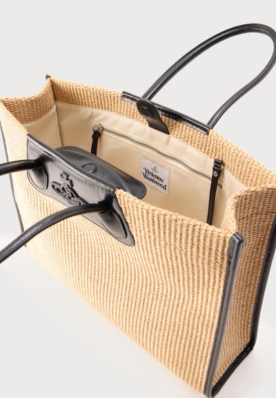 Υφαντή μπεζ τσάντα tote με μαύρες δερμάτινες λαβές, μαύρο περίγραμμα, εσωτερική τσέπη με φερμουάρ και λογότυπο Vivienne Westwood στην μπροστινή όψη.