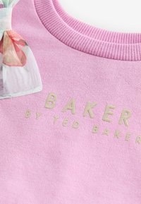 Ružový bavlnený sveter s rebrovaným výstrihom, s pozláteným embosovaným textom "BAKER by TED BAKER" a kvetinovým vzorom mašle na boku.