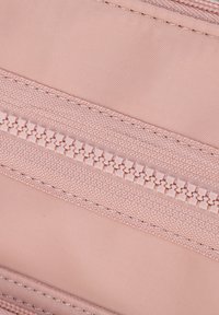 Tessuto rosa chiaro con una finitura testurizzata, caratterizzato da un evidente dettaglio della cerniera. Superficie liscia con cuciture a contrasto lungo i bordi.