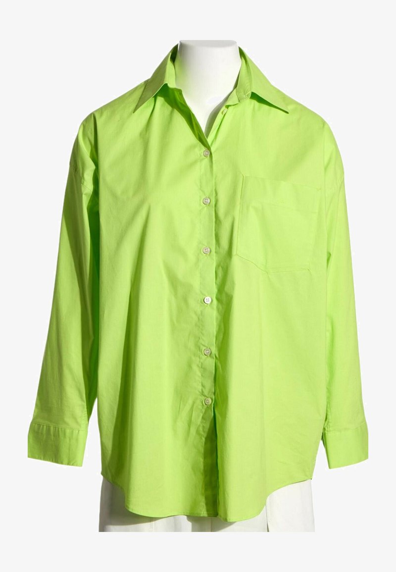 Chemise verte citron à manches longues boutonnée avec col et poche poitrine exposée sur un buste de mannequin blanc.