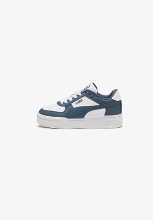 Baskets en cuir bleu et blanc à coupe basse, avec embout perforé, lacets blancs et semelle épaisse blanche. Logo Puma sur le côté.