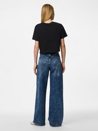 Melnā īsajā T-kreklā apakšā valkātas platās kājas zilo denima džinsi ar gaismas mazgājumu, aizmugurējām kabatām un brīvu piegriezumu.