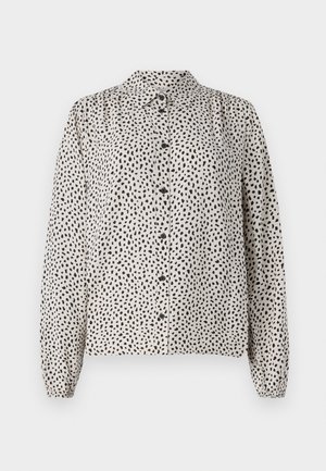 Knappe skjorte i kremfarge med svarte prikker, med krage, lange ermer og elastiske mansjetter. Laget av et lett og glatt stoff.