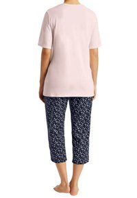 Lys rosa bomulds-T-shirt med korte ærmer, parret med navy capri-bukser med et hvidt blomstermønster. Simpel, afslappet pasform.