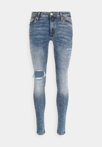 Jeans de mezclilla azul ajustados con un diseño desgastado, que presentan desgarros en las rodillas y un clásico diseño de cinco bolsillos.