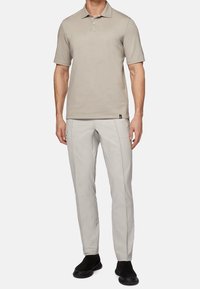 Beige polo shirt with short sleeves, paired with light gray pants and black slip-on shoes. Simple design, smooth texture, and fitted style.