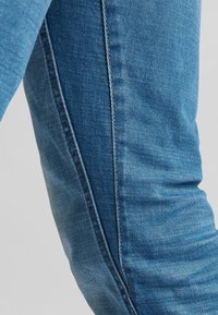 Modré džíny ze silné denimové látky ve slim fit, s viditelným prošíváním podél postranních švů a mírným vyblednutím pro strukturovaný vzhled.