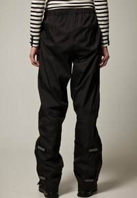 Černé voděodolné kalhoty z lehkého materiálu, s elastickým pasem a nastavitelnými manžetami s reflexními prvky.