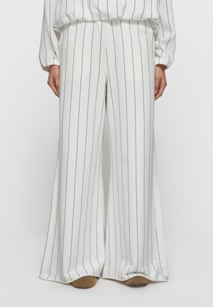 Białe spodnie z szerokimi nogawkami z cienkimi czarnymi pionowymi paskami. Miękki materiał o gładkiej fakturze. Elastyczny pas i minimalistyczny design.