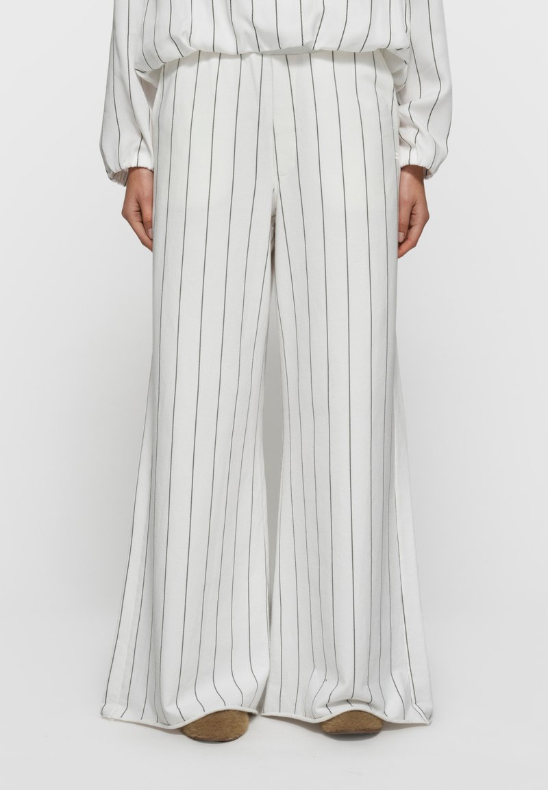Pantalon blanc à jambes larges avec fines rayures verticales noires. Tissu doux avec une texture lisse. Taille élastique et design minimaliste.