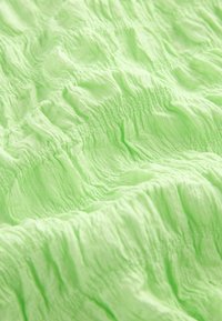 Tejido texturizado verde claro con un patrón ondulado, que presenta suaves pliegues en forma de ondas y una apariencia ligeramente translúcida.
