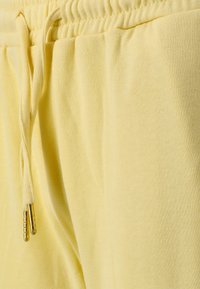 Gula sweatpants i ett strukturerat tyg, med ett elastiskt midjeband och en dragsko med guldmetallspetsar.