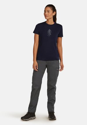 Camiseta de manga corta azul marino con un gráfico de un árbol blanco en la parte frontal, combinada con pantalones grises y botas de senderismo negras. Diseño simple y funcional.