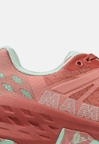 Scarpe da ginnastica corallo e menta con tomaia testurizzata, dettagli in rete, fori a forma di diamante e branding prominente. Presentano un collo imbottito e lacci piatti.