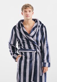 Accappatoio a righe in navy e grigio chiaro, realizzato in tessuto morbido e testurizzato. Presenta un ampio colletto, chiusura con cintura e tasche laterali.