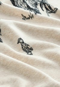 Beige stof med fin tekstur, der viser en sort blækillustration af en and blandt svage skitser af andre dyr.