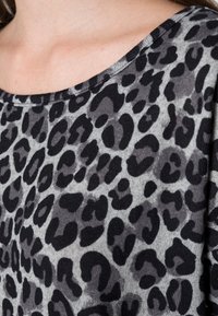 Grau-schwarzer Leopardenmuster-Stoff mit weicher Textur, ausgestattet mit einem runden Ausschnitt und leichtem Glanz. Sichtbares Paneeldesign.