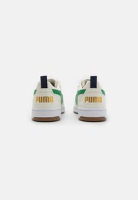 Weiße Sneaker mit grünen Akzenten, strukturierten Seiten und marineblauen Fersen-Schlaufen. Verfügt über das goldene PUMA-Logo auf der Rückseite und eine braune Gummisohle.
