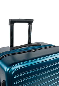 Maleta rígida azul con estrías horizontales, asa telescópica negra y una cremallera a juego. Textura suave y diseño robusto.