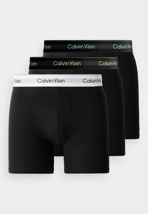 Black boxer briefs set featuring elastic waistbands in white, black, and green with "Calvin Klein" branding. Soft fabric, fitted design.