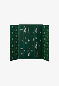 Calendrier de l'Avent en carton vert avec des portes numérotées, arborant un design minimaliste et la marque "essie" en blanc sur le devant.