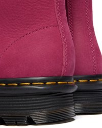 Botas de tornozelo em camurça rosa com sola preta, apresentando costura amarela e acabamento texturizado. O design destaca costuras curvas na parte superior.