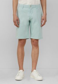 Lichtblauwe katoen shorts, met een platte voorkant, riemlussen en een enkele knoopsluiting. Draagt men met witte sneakers.