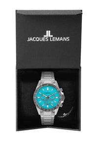 Klocka i rostfritt stål med en turkos urtavla, silverdetaljer, tre sub-dialar och tachymetriska markeringar. Levereras i en svart låda.