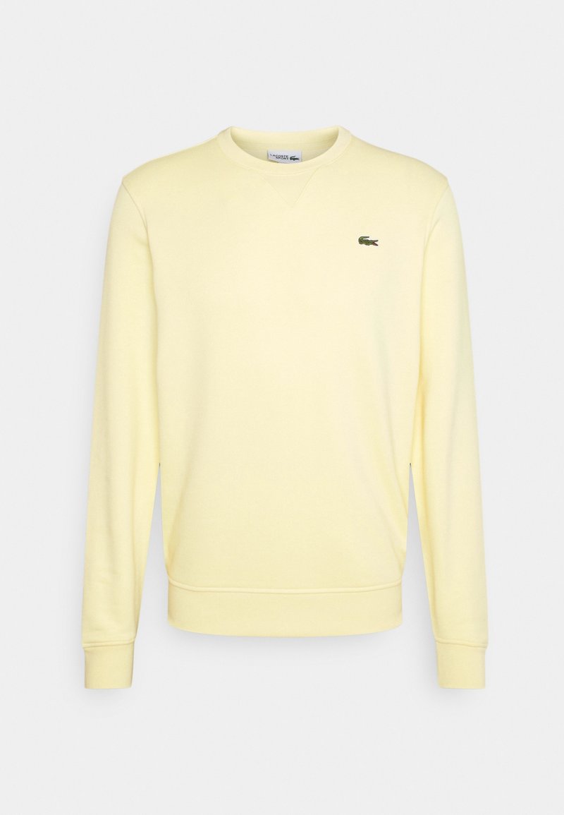 Sweat-shirt col rond jaune clair à manches longues avec petit logo crocodile vert sur la poitrine gauche.