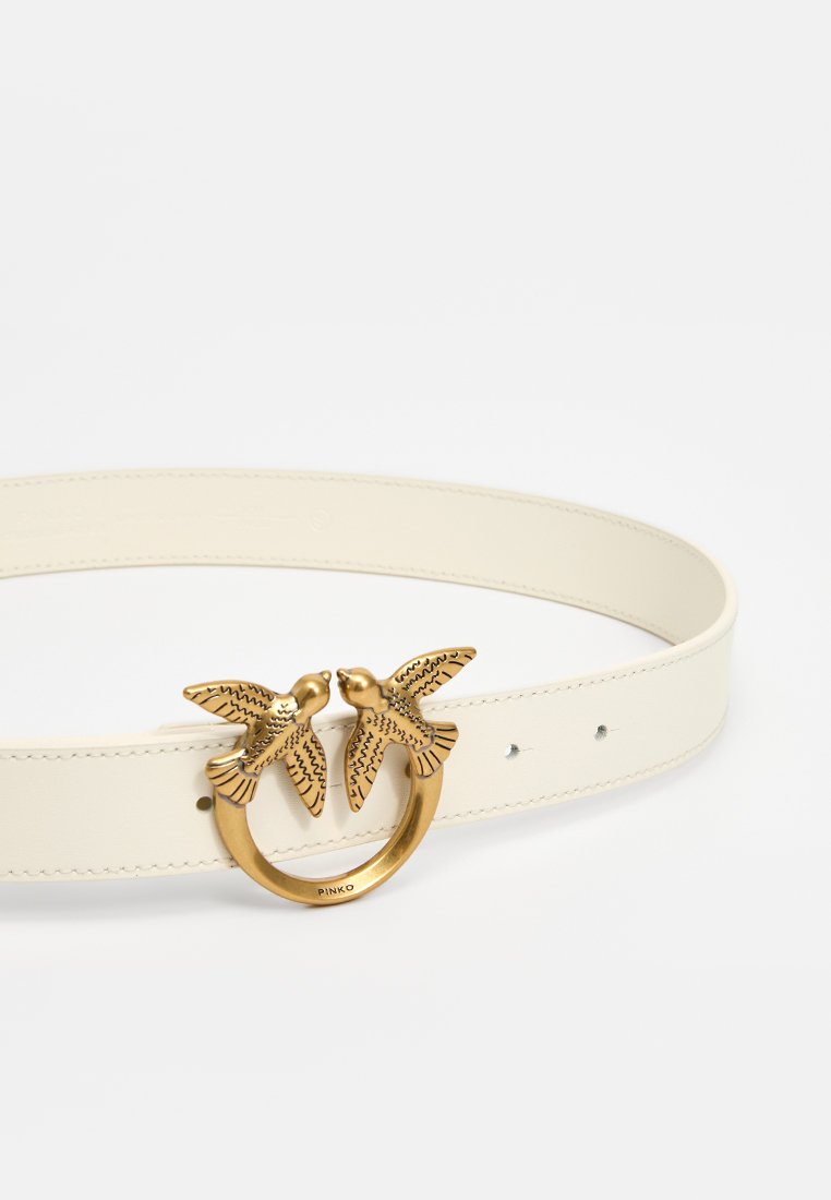 Cintura in pelle bianca con una fibbia rotonda in tonalità oro e due uccelli finemente decorati. Texture liscia con più fori per la regolazione.