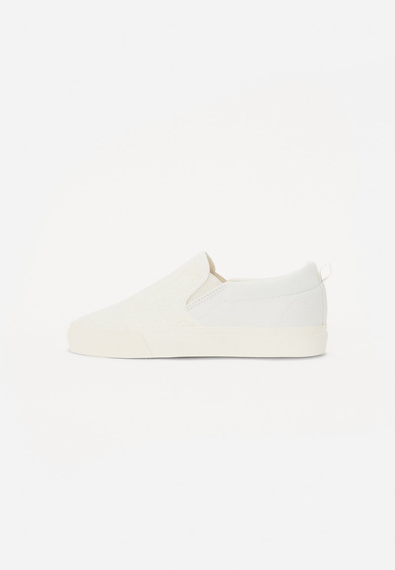 Biele slip-on tenisky s textúrovanou prednou časťou, hladkými bokmi a minimalistickým dizajnom so subtilným pútkom na zadnej strane pre ľahké obúvanie.