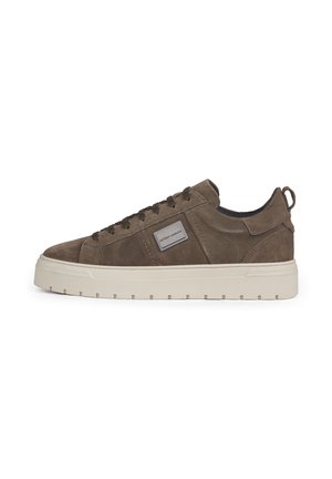 Bruine suède lage sneaker met witte dikke zool, veters aan de voorkant, logo patch aan de zijkant en een hieltreklus.