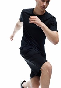 Camiseta atlética negra y pantalones cortos hechos de un tejido ligero y suave. Diseño ajustado con mangas cortas y escote redondo.