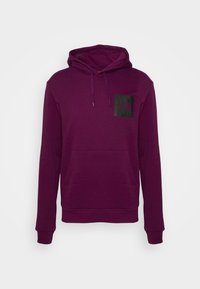 Sweat à capuche violet, à enfiler, avec poche kangourou devant, capuche à cordon de serrage et petit logo sombre sur le haut gauche de la poitrine.