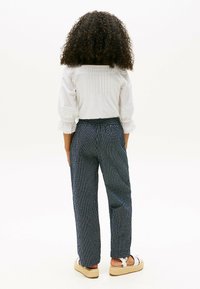 Blusa bianca con texture e maniche a sbuffo abbinata a pantaloni a righe blu navy. I pantaloni hanno una vestibilità comoda e una cintura elastica.