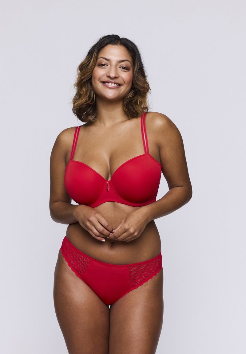 Rode beha met een gladde afwerking en ritssluiting, met verstelbare bandjes. Bijpassende rode panties met een gestructureerd kantdetail op de tailleband.