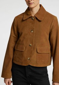 Brun ruskindjakke med krave, knaplukning og to klaplommer. Designet er cropped med lange ærmer og en glat tekstur.