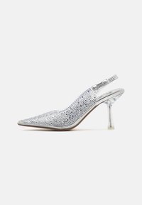 Sudraba slingback augstpapēžu kurpe ar norādītu pirkstu, pārklāta ar mirdzošiem rhinestone akmeņiem un ar caurspīdīgu papēdi. Gluda, spīdīga apdare.