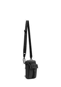 SVARTAXELVÄNDBAG MED TEXTURERAD REM, FLERA ZIPPERFAKTA, EN STOR FRAMFLIK OCH EN KARABINHÄNGARE FÖR SÄKER ANSLUTNING.