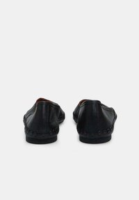 Loafers negri din piele cu detalii cusute pe talpă. Spate rotunjit, textură netedă și design de profil redus.