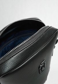 Zaino in pelle nera texture con apertura a zip, caratterizzato da una fodera interna blu e un logo ben visibile sul pannello frontale.