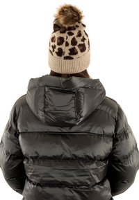 Giacca a vento nera con cappuccio, caratterizzata da una finitura lucida e trapuntata. Abbinata a un berretto in maglia beige con stampa leopardata marrone e pompon.