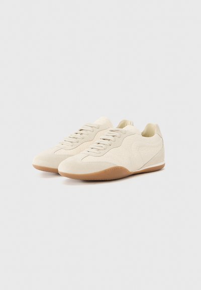 Παπούτσια σε κρεμ χρώμα με υφασμάτινη επιφάνεια, διαθέτουν μαξιλαρωτό περίβλημα, σχέδιο με κορδόνια και καφέ ελαστική σόλα.