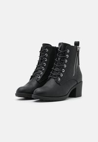 Botas negras hasta el tobillo con un acabado de cuero texturizado, punta redonda, cordones en la parte delantera, cremallera lateral y tacón cuadrado. Suela de goma para tracción.