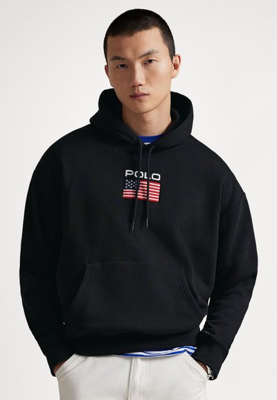 Svart hettegenser med frontlomme, med brodert "POLO"-logo og amerikansk flaggdesign. Bomullsstoff, avslappet passform.