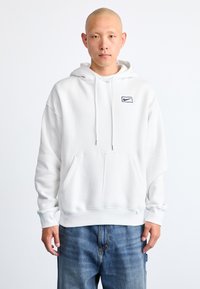 Moletom com capuz branco, com bolso frontal, punhos e barra canelados. Apresenta um pequeno logo da Nike em azul marinho no lado esquerdo do peito. Material em fleece macio.