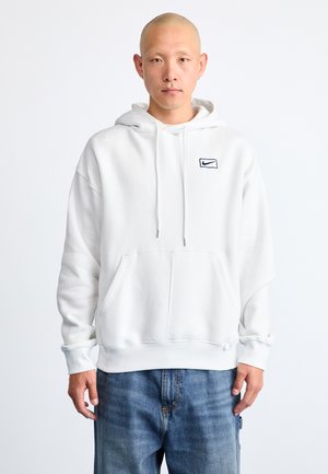 White hooded sweatshirt with front pocket, ribbed cuffs, and hem. Features a small navy Nike logo on the left chest. Soft fleece material.
